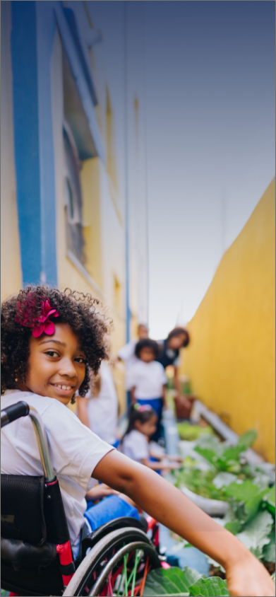 Image d’une jeune fille souriante en fauteuil roulant avec une  fleur rose dans les cheveux