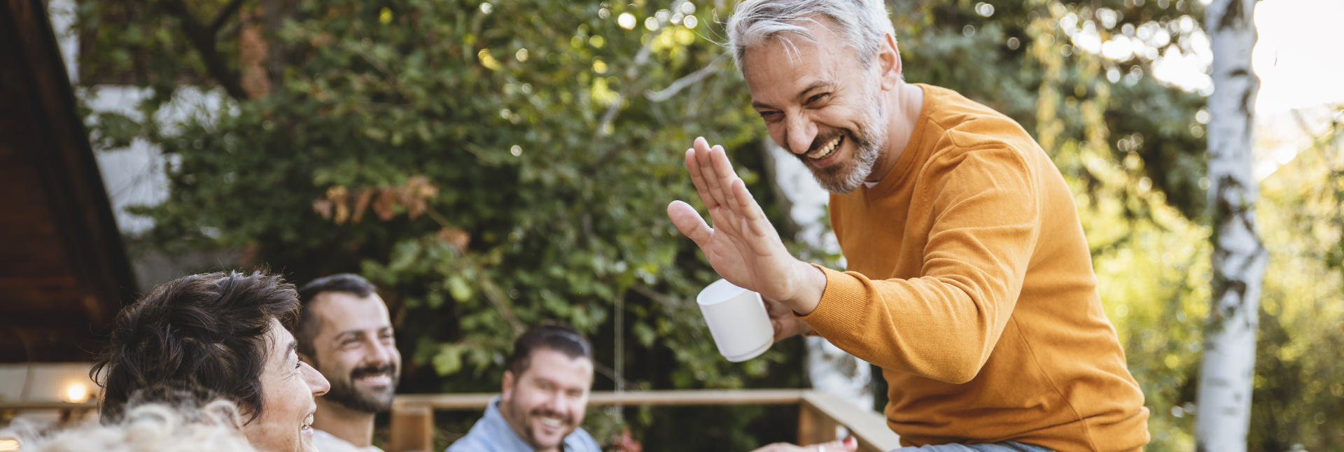 Image d’un homme souriant assis sur une rambarde et faisant un signe de main aux personnes en face de lui