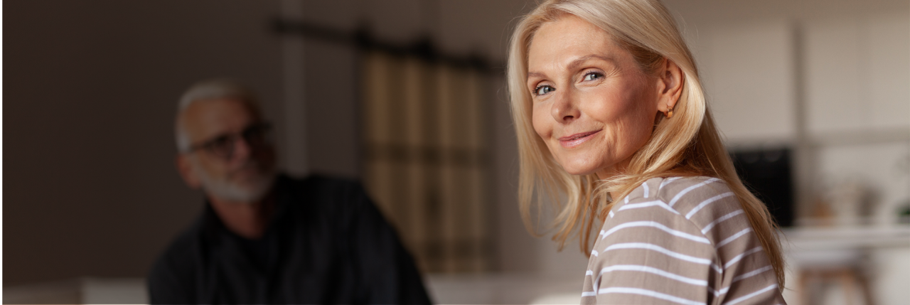 Femme blonde qui sourit avec un homme en arrière plan