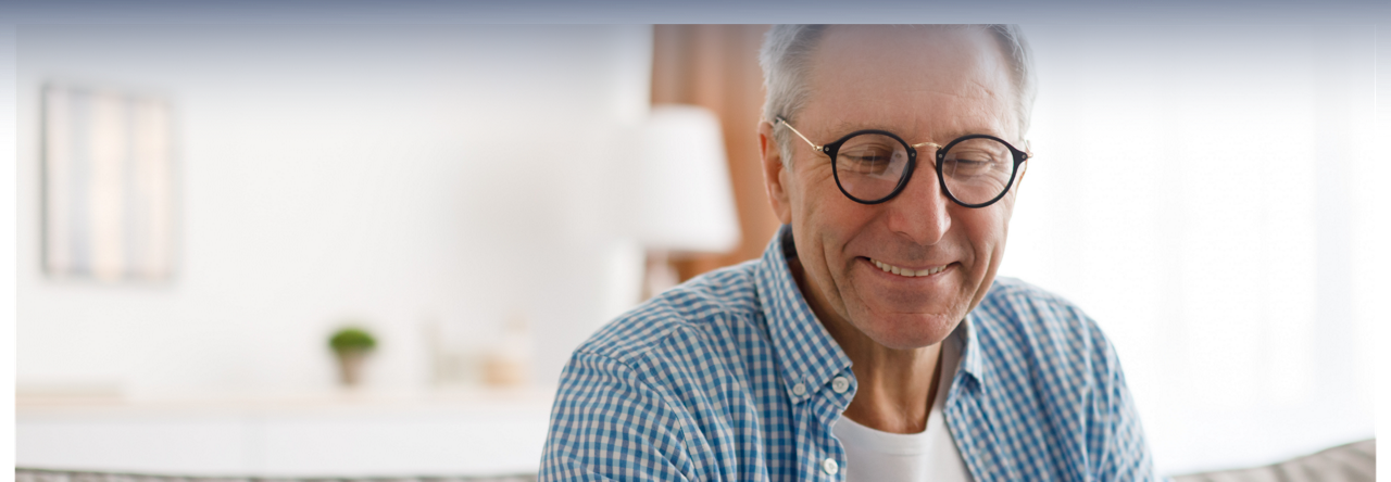 Image d’un homme souriant en chemise et portant des lunettes